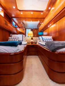 Luxury cabin with single beds and soft lighting aboard the boat. Luxury cabin with two single beds in polished wood, soft lighting, and elegant decor, creating a cozy and sophisticated atmosphere.