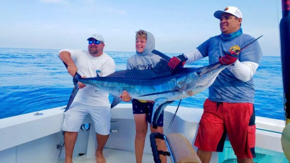 "Cabo Fishing Report: Two anglers celebrating an impressive marlin catch on a charter boat in Cabo San Lucas, Mexico."